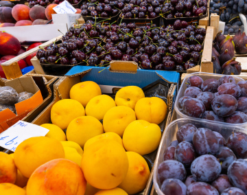 Sprzedaż owoców na bazarze. Śliwki i czereśnie w skrzynkach, zdjęcie stockowe