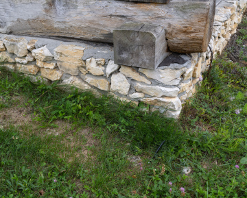 Kamienna podmurówka pod budynkiem z drewna