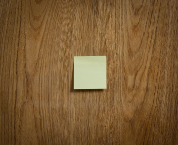 Żółta karteczka przyklejona do drewnianej powierzchni.