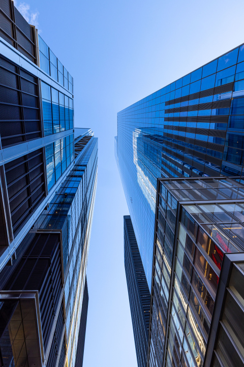 Widok z dołu na nowoczesne szklane wieżowce w centrum miasta na tle błękitnego nieba; zdjęcie stockowe