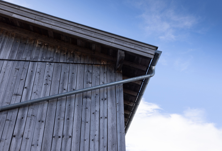 Drewniana ściana budynku z metalową rynną.